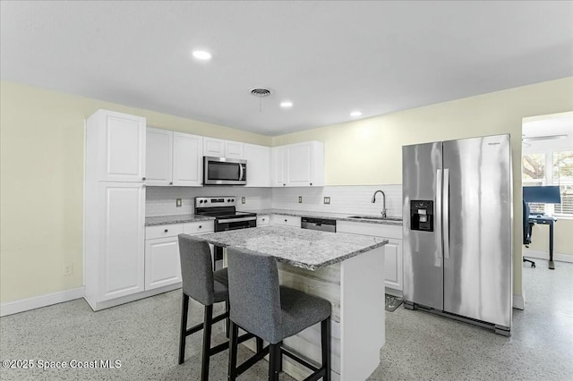 kitchen with visible vents, decorative backsplash, appliances with stainless steel finishes, white cabinets, and a sink