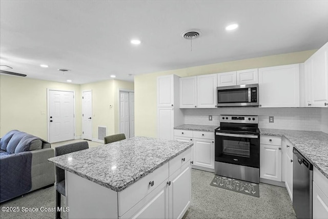 kitchen featuring recessed lighting, light speckled floor, appliances with stainless steel finishes, and open floor plan