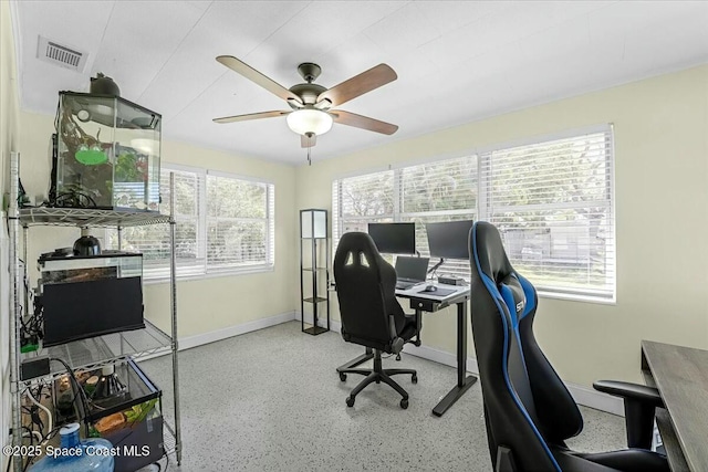 home office featuring speckled floor, baseboards, visible vents, and ceiling fan