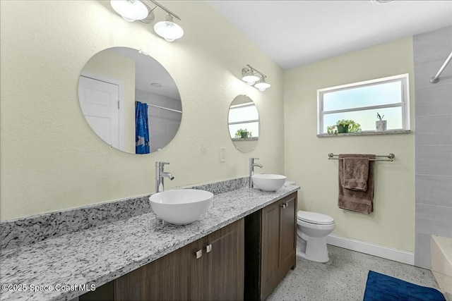 bathroom featuring double vanity, curtained shower, speckled floor, and a sink