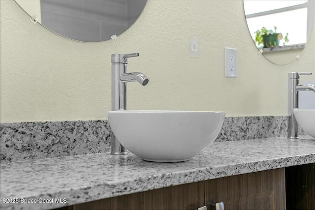 interior details featuring vanity and a textured wall