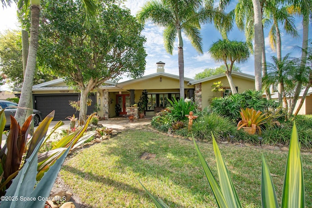 view of front of house featuring a front yard, a garage, and stucco siding