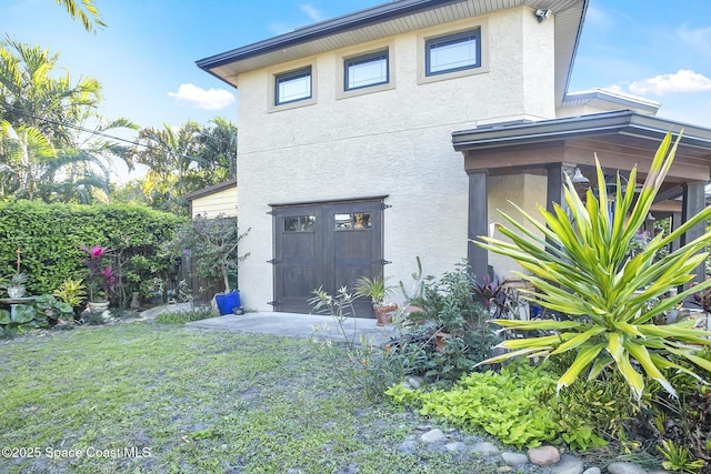 view of side of property with stucco siding and a yard