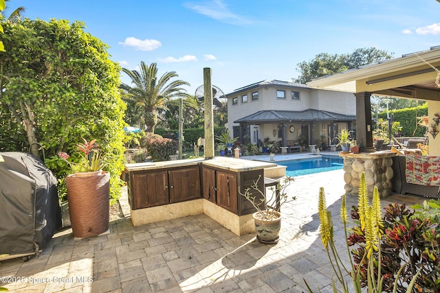 pool with grilling area and a patio