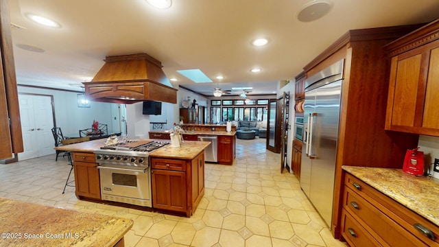 kitchen with recessed lighting, light stone countertops, high quality appliances, and island range hood