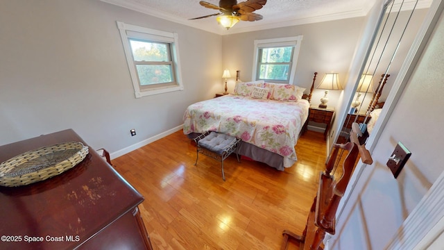 bedroom with light wood finished floors, a textured ceiling, crown molding, and baseboards