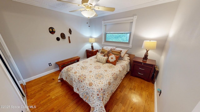 bedroom featuring light wood-type flooring, baseboards, ceiling fan, and crown molding