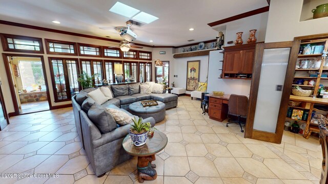 living room with a ceiling fan, baseboards, a skylight, recessed lighting, and ornamental molding