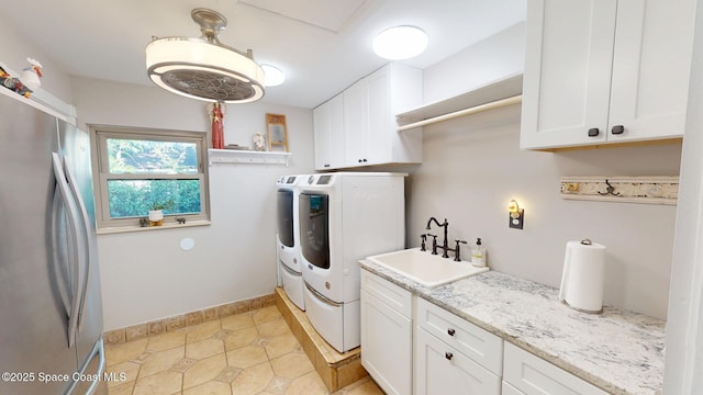 washroom with a sink, baseboards, cabinet space, and independent washer and dryer