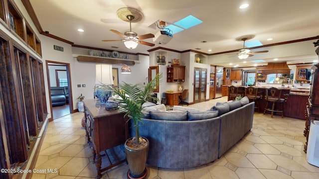 living room with a ceiling fan, crown molding, a skylight, and recessed lighting