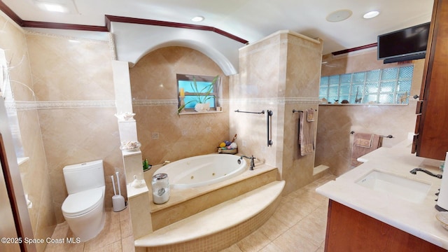 bathroom featuring toilet, a whirlpool tub, tile patterned floors, tile walls, and a sink