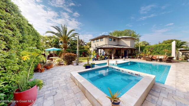 view of pool with a patio area and a pool with connected hot tub