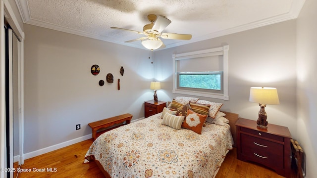 bedroom with a closet, baseboards, wood finished floors, and crown molding