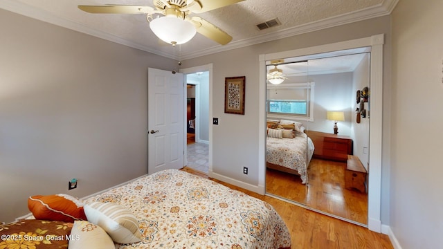 bedroom with visible vents, baseboards, light wood-style floors, and ornamental molding