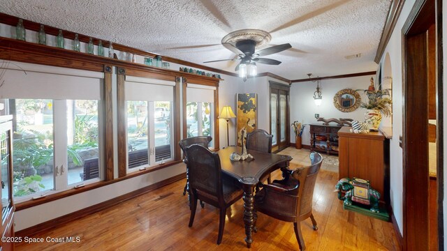 dining area featuring a ceiling fan, baseboards, ornamental molding, light wood-style floors, and a textured ceiling