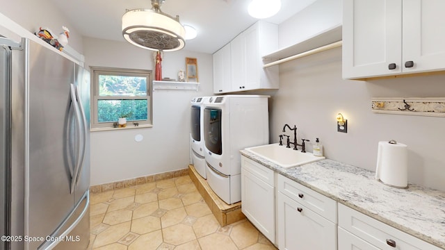 laundry area with baseboards, light tile patterned floors, washer and dryer, cabinet space, and a sink