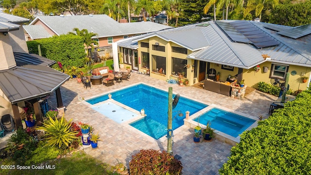 view of swimming pool with a pool with connected hot tub, outdoor lounge area, a fenced backyard, a sunroom, and a patio