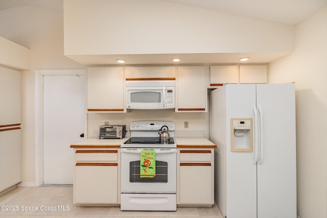 kitchen featuring light tile patterned floors, white appliances, light countertops, and vaulted ceiling