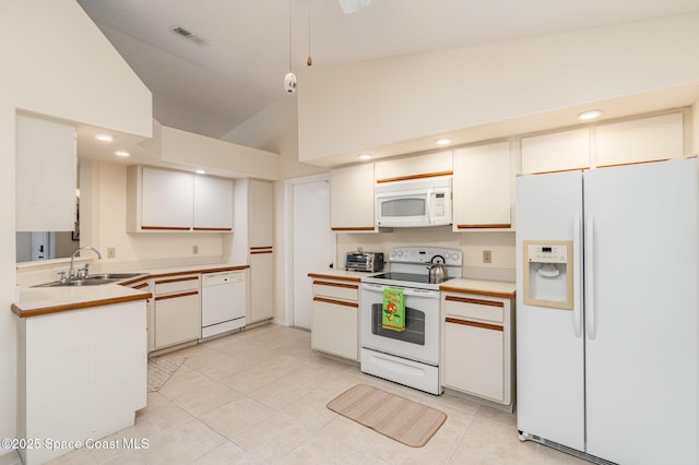 kitchen featuring visible vents, light countertops, lofted ceiling, white appliances, and a sink