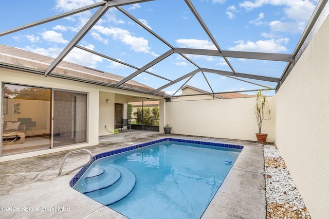 outdoor pool featuring glass enclosure and a patio