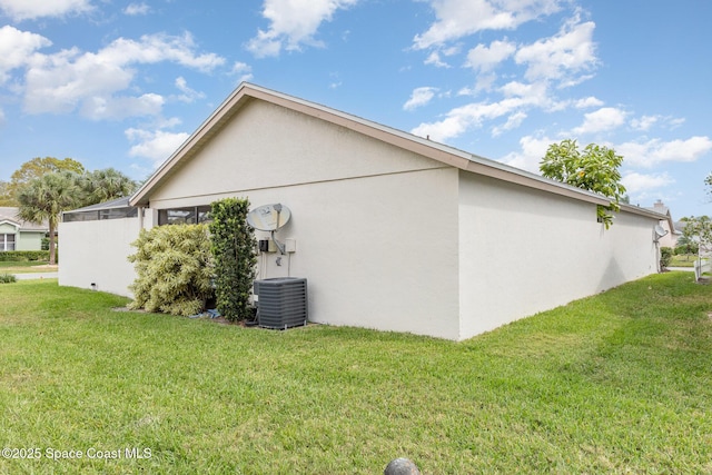 view of side of home with stucco siding, a yard, and central AC unit