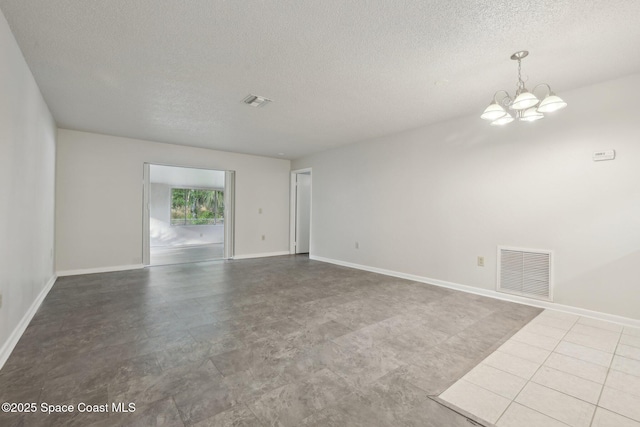 unfurnished room with a notable chandelier, baseboards, visible vents, and a textured ceiling