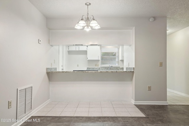 kitchen featuring visible vents, an inviting chandelier, hanging light fixtures, white cabinets, and a textured ceiling