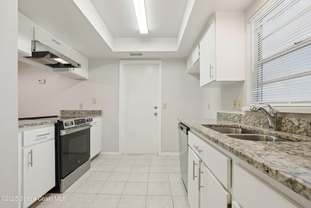 kitchen featuring light tile patterned floors, a tray ceiling, a sink, stainless steel appliances, and white cabinets