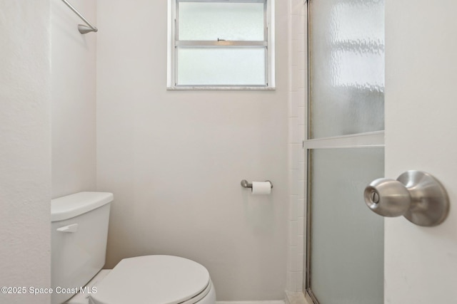 bathroom featuring toilet and a shower with door