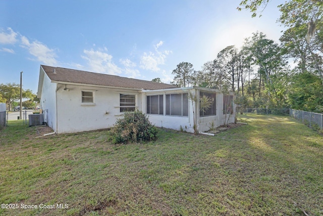 rear view of property with central AC unit, a lawn, a fenced backyard, and a sunroom