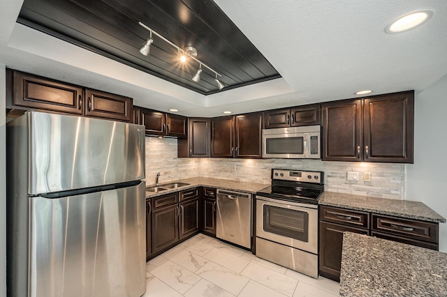 kitchen with marble finish floor, a sink, backsplash, appliances with stainless steel finishes, and a raised ceiling