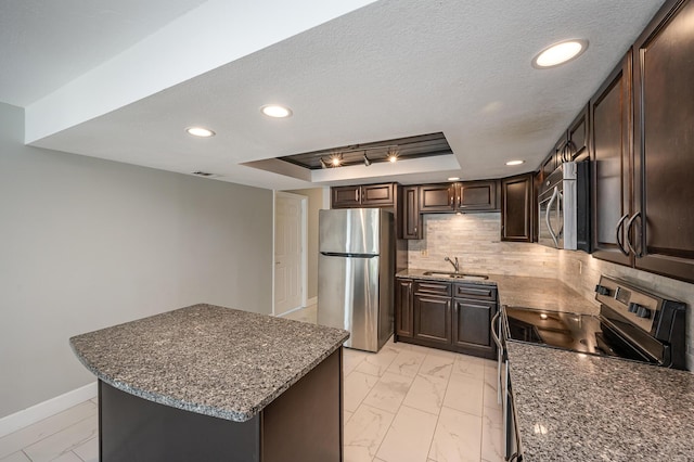 kitchen with tasteful backsplash, dark brown cabinetry, a tray ceiling, marble finish floor, and stainless steel appliances