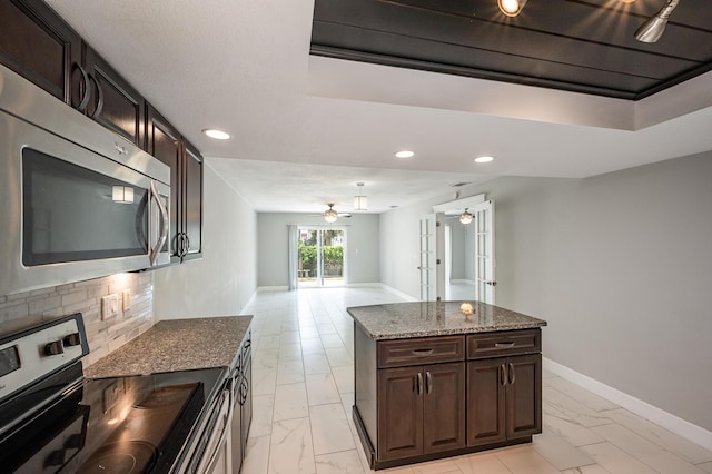 kitchen featuring dark stone countertops, baseboards, marble finish floor, and appliances with stainless steel finishes