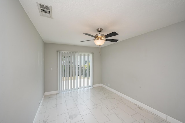 spare room with visible vents, marble finish floor, a ceiling fan, and baseboards