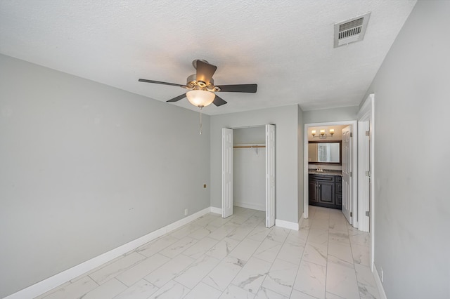 unfurnished bedroom with visible vents, baseboards, a closet, a textured ceiling, and marble finish floor