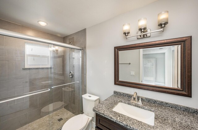 bathroom with a shower stall, toilet, and vanity