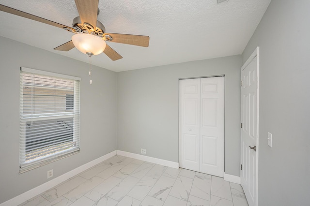 unfurnished bedroom with multiple windows, baseboards, marble finish floor, and a closet