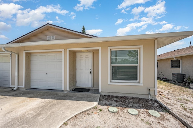 view of front of property featuring concrete driveway, an attached garage, and central AC