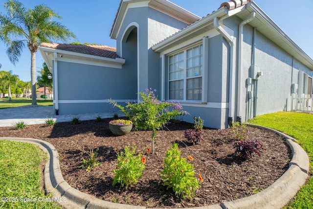 view of side of home with a tiled roof and stucco siding