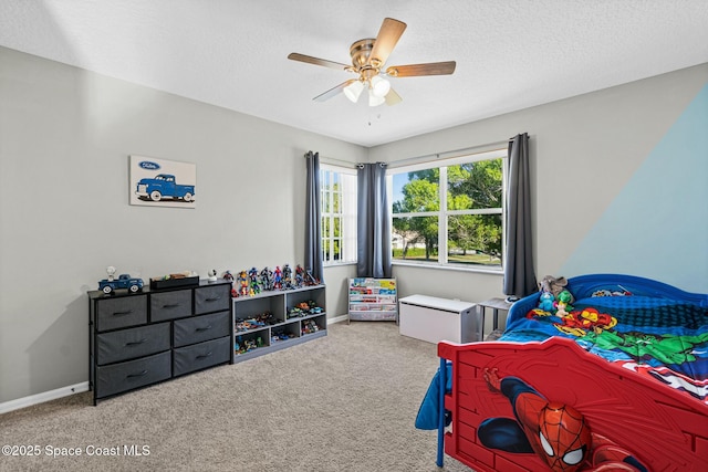 carpeted bedroom with ceiling fan, a textured ceiling, and baseboards