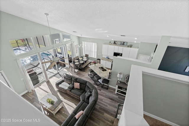 living room with baseboards, a textured ceiling, and wood finished floors