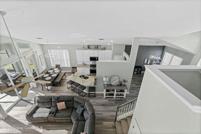 living area with baseboards, a textured ceiling, an inviting chandelier, and wood finished floors