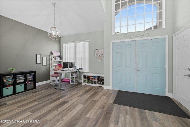 entrance foyer with a chandelier, a high ceiling, baseboards, and wood finished floors