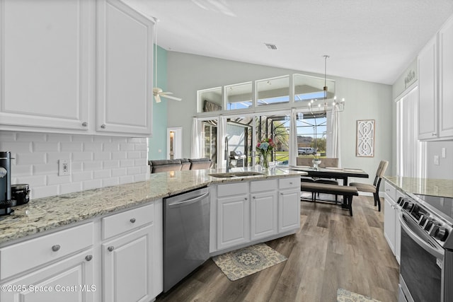 kitchen with dark wood finished floors, lofted ceiling, a sink, stainless steel appliances, and tasteful backsplash