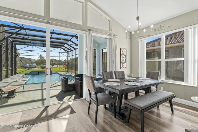 dining area featuring baseboards, high vaulted ceiling, wood finished floors, and a sunroom