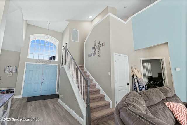 foyer entrance with a notable chandelier, baseboards, a high ceiling, and wood finished floors