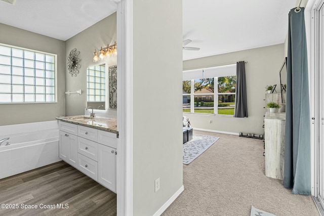 full bath featuring baseboards, a garden tub, ceiling fan, and vanity