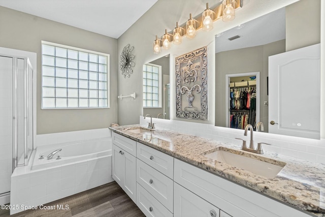 bathroom with a bath, visible vents, wood finished floors, and a sink