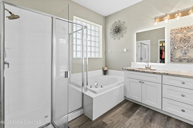 bathroom with wood finished floors, vanity, a bath, and a shower stall