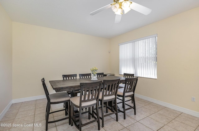 dining space featuring light tile patterned floors, a ceiling fan, and baseboards